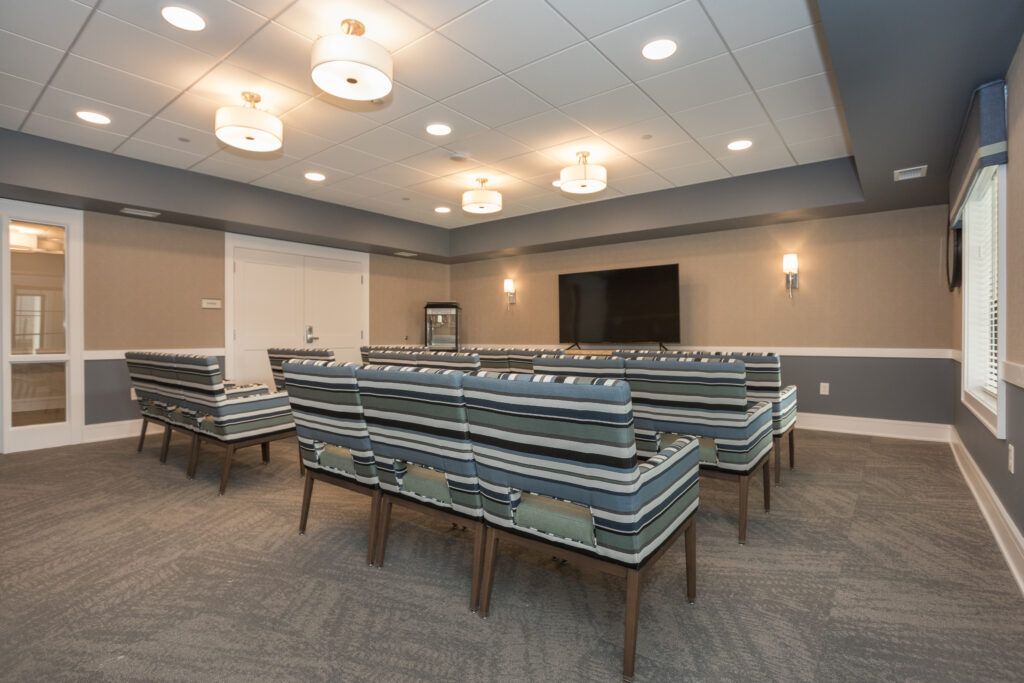 A modern conference room equipped with seating, a projector screen, and a television.