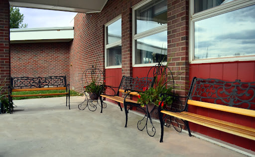 A row of elegantly designed benches with planters, set against a brick wall and large windows.