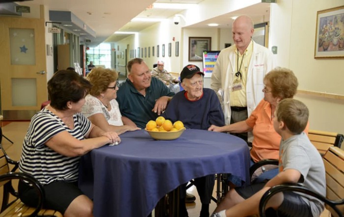 A group of people gathered around a table, engaging in friendly conversation indoors.