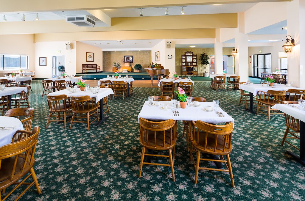 A spacious dining area with neatly arranged tables and chairs, featuring a patterned carpet.