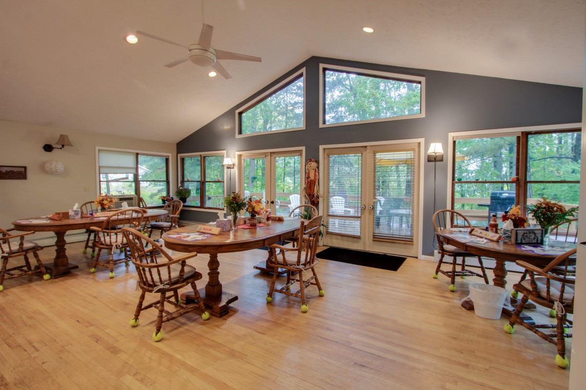 A spacious dining area with wooden furniture and large windows allowing natural light to fill the room.