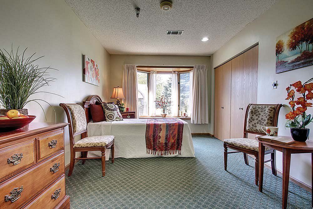 A cozy bedroom with ample natural light coming through a large window, featuring comfortable furniture and tasteful decor.