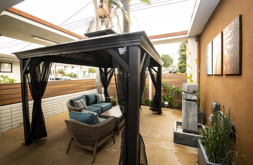 A stylish outdoor patio with a gazebo, comfortable seating, and modern decor.