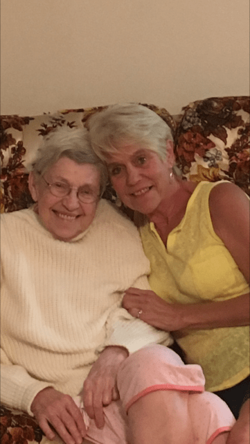 Two women sitting together on a couch, smiling warmly.