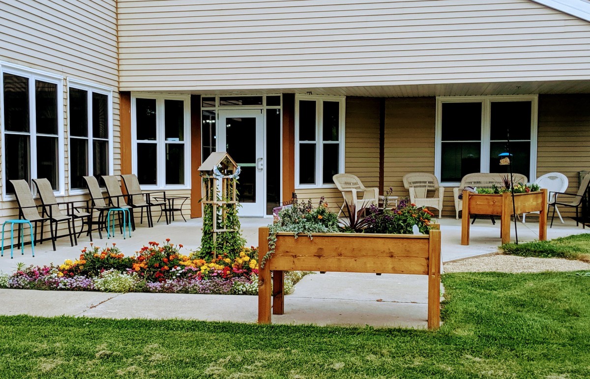 A cozy outdoor area with raised garden beds and seating in front of a building.