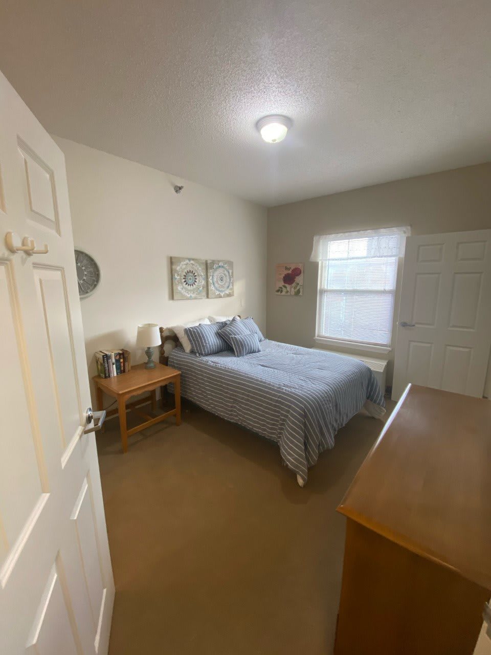 A cozy bedroom with a neatly made bed, nightstand, and dresser.