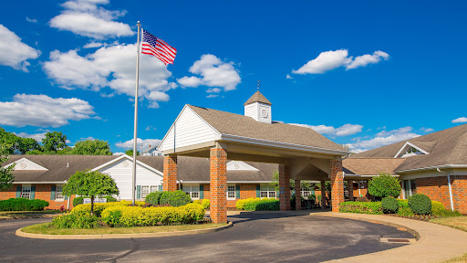A welcoming entrance with an American flag under a bright blue sky and fluffy clouds.