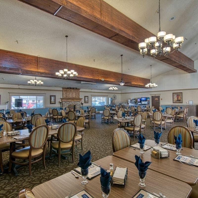 An elegant dining room with neatly arranged tables and chandeliers.