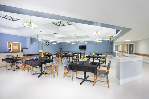 A modern dining area featuring neatly arranged tables and chairs under warm lighting.