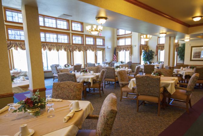 A spacious dining room with elegantly set tables and comfortable seating.