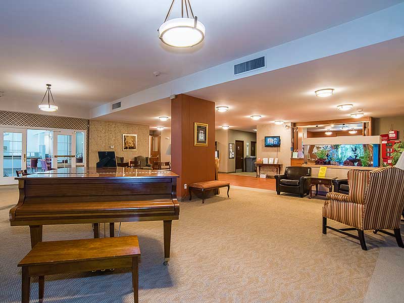 A spacious lobby with a piano and seating area, featuring warm lighting.