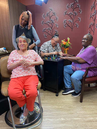 Residents enjoying a community activity at a care facility, with one resident receiving a manicure.