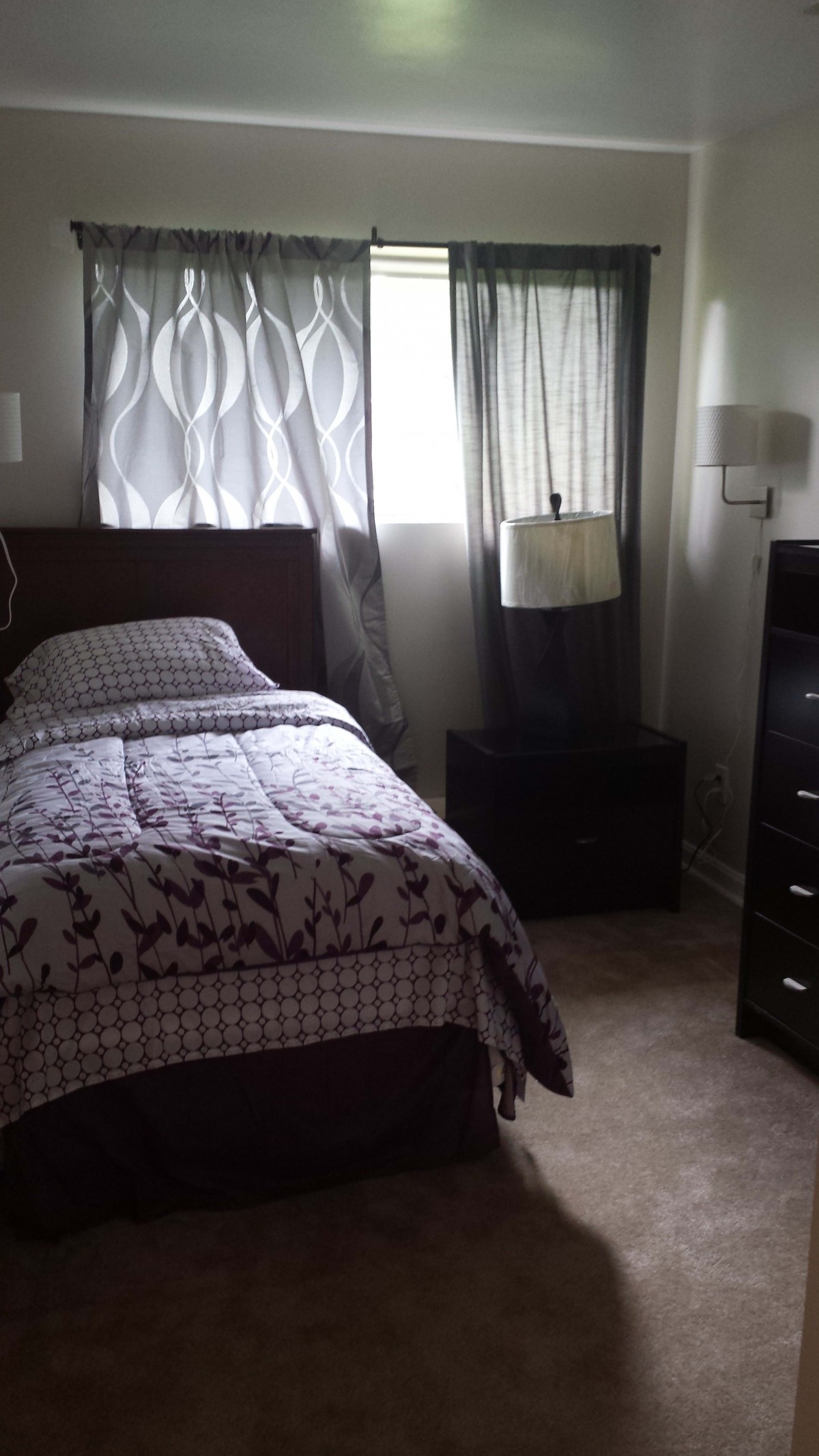 A cozy bedroom with a single bed, nightstand, and dresser.