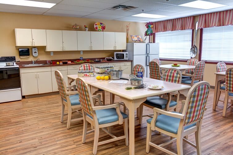 A cozy kitchen and dining area with a table, chairs, cabinets, and appliances.
