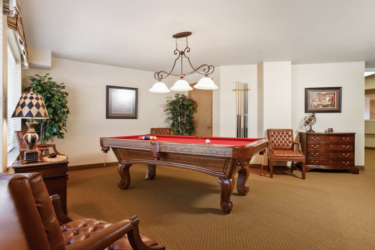 A cozy billiard room featuring a red-felt pool table and elegant decor.