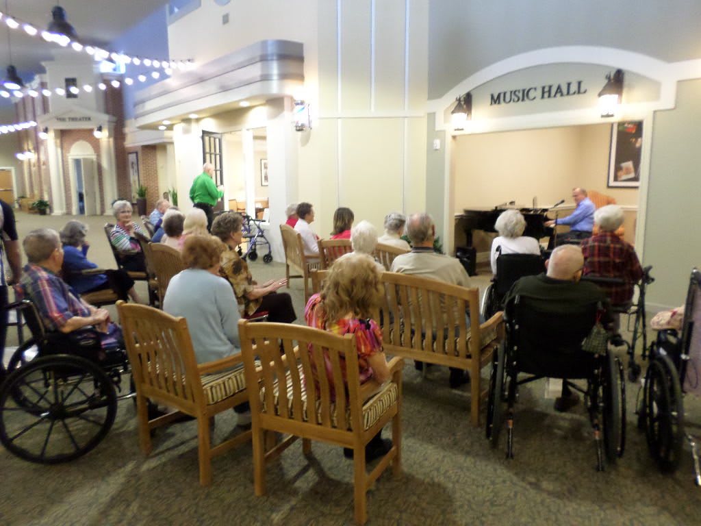 A group of senior citizens seated in a music hall, attending an event.