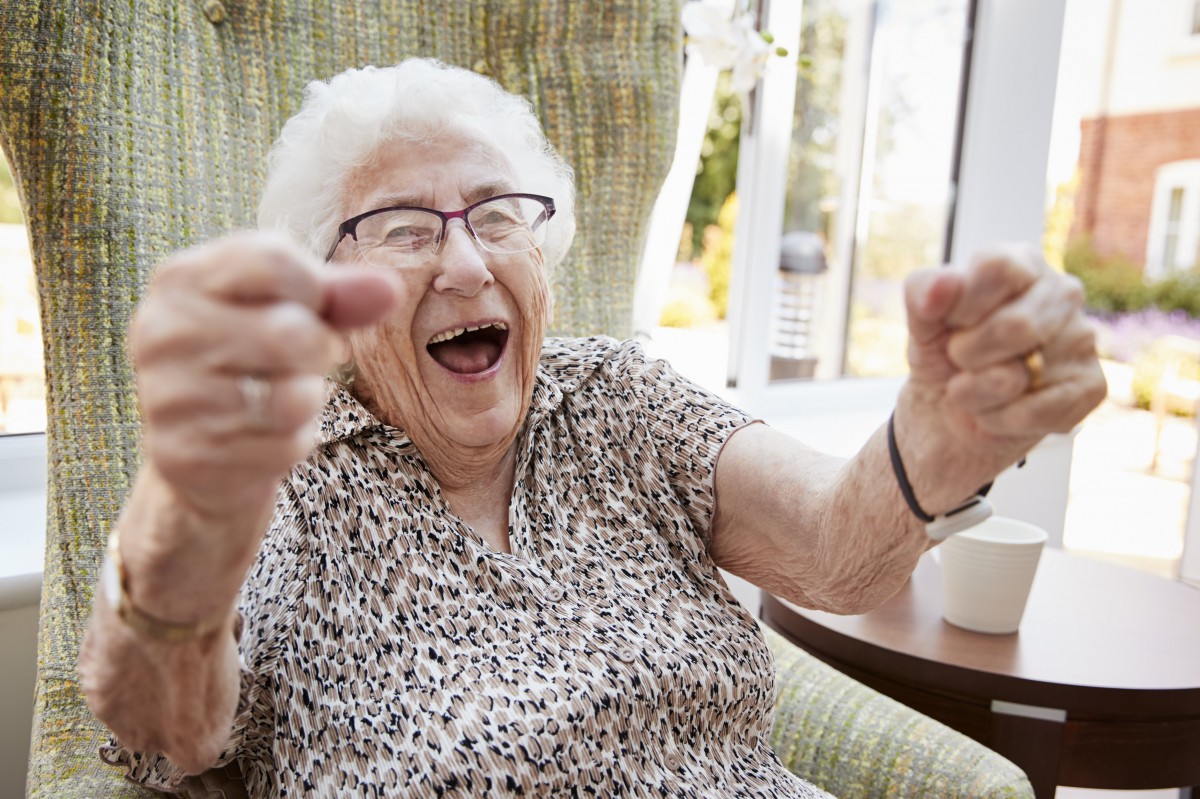 An elderly woman laughing joyfully indoors.