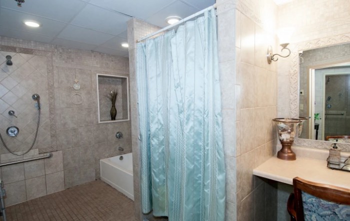 A clean and modern bathroom with a bathtub and a blue shower curtain.