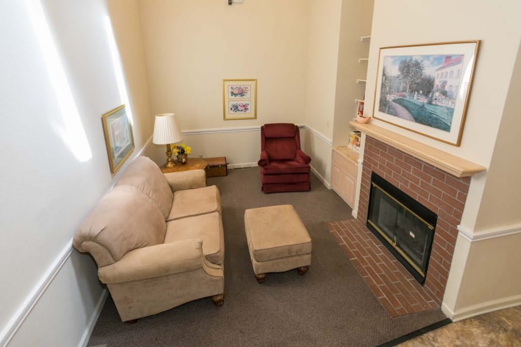 A cozy living room with a sofa, armchair, and fireplace.