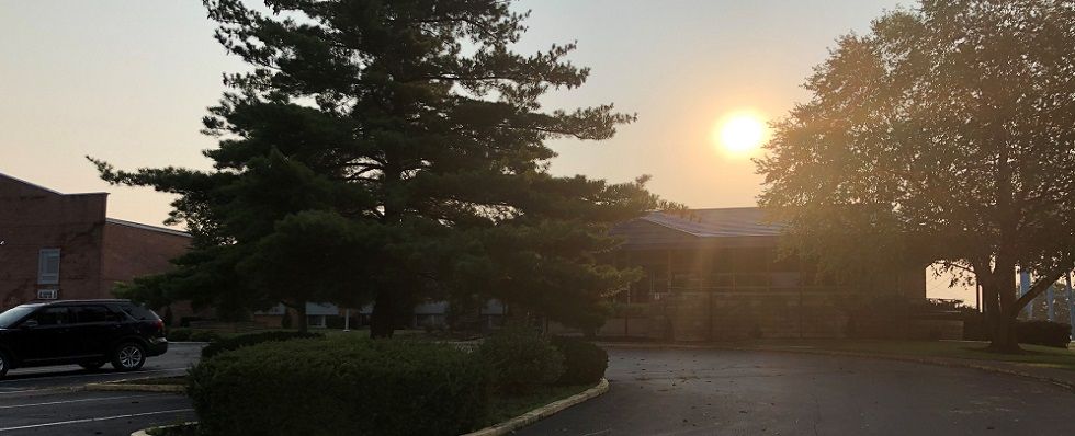 A serene sunset over a driveway surrounded by trees.