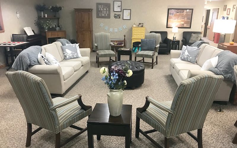 A cozy living room setup with sofas, chairs, and a central table adorned with a vase of flowers.