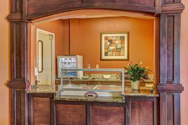 A hotel reception area with a wooden counter, artwork on the orange wall, and a decorative plant.