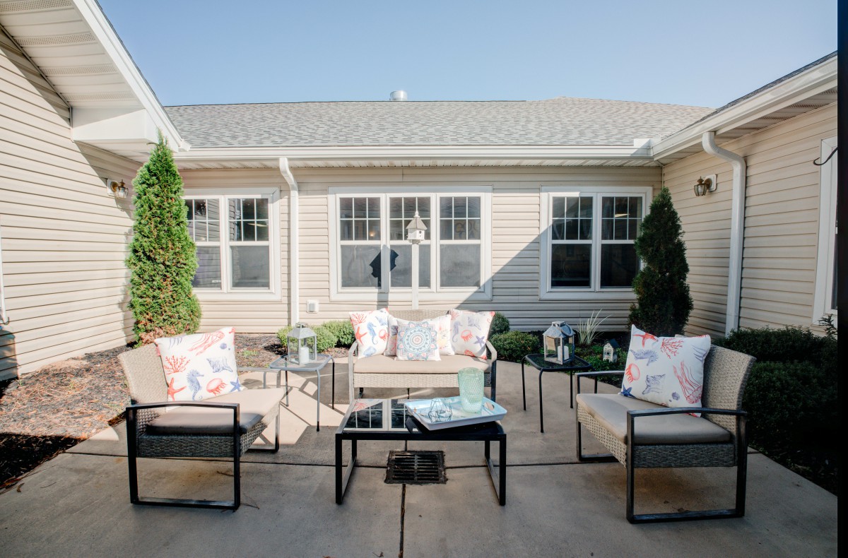 A cozy outdoor patio area featuring modern garden furniture set against a house exterior on a sunny day.