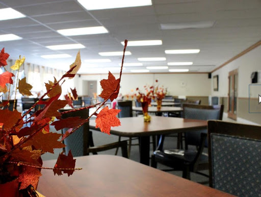 A spacious dining area decorated with autumn-themed centerpieces, featuring tables and chairs arranged for gatherings.
