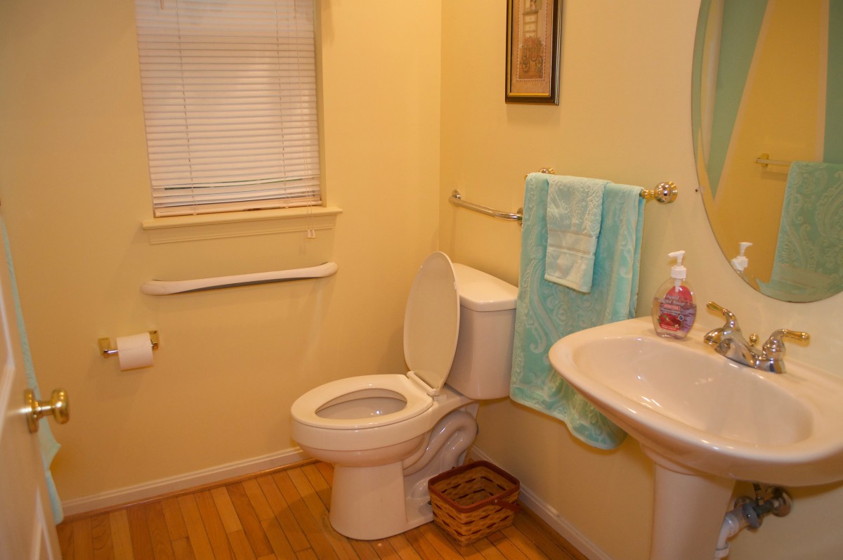 A small, neatly arranged bathroom with a toilet, sink, and a towel hanging nearby.