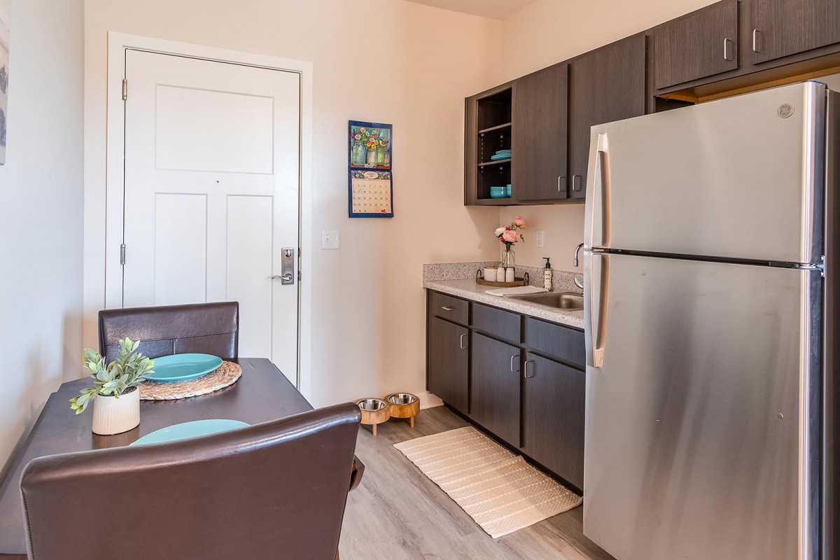 A modern kitchen with dark cabinets and a dining table set for two.