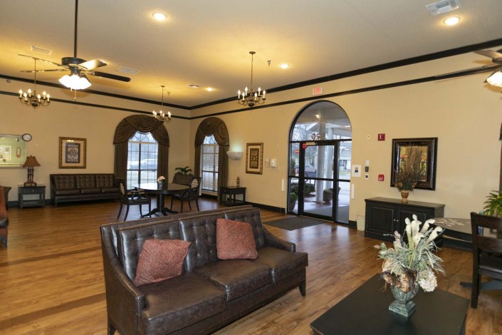 A cozy and elegantly decorated living room with a sofa, wooden floor, and large windows.