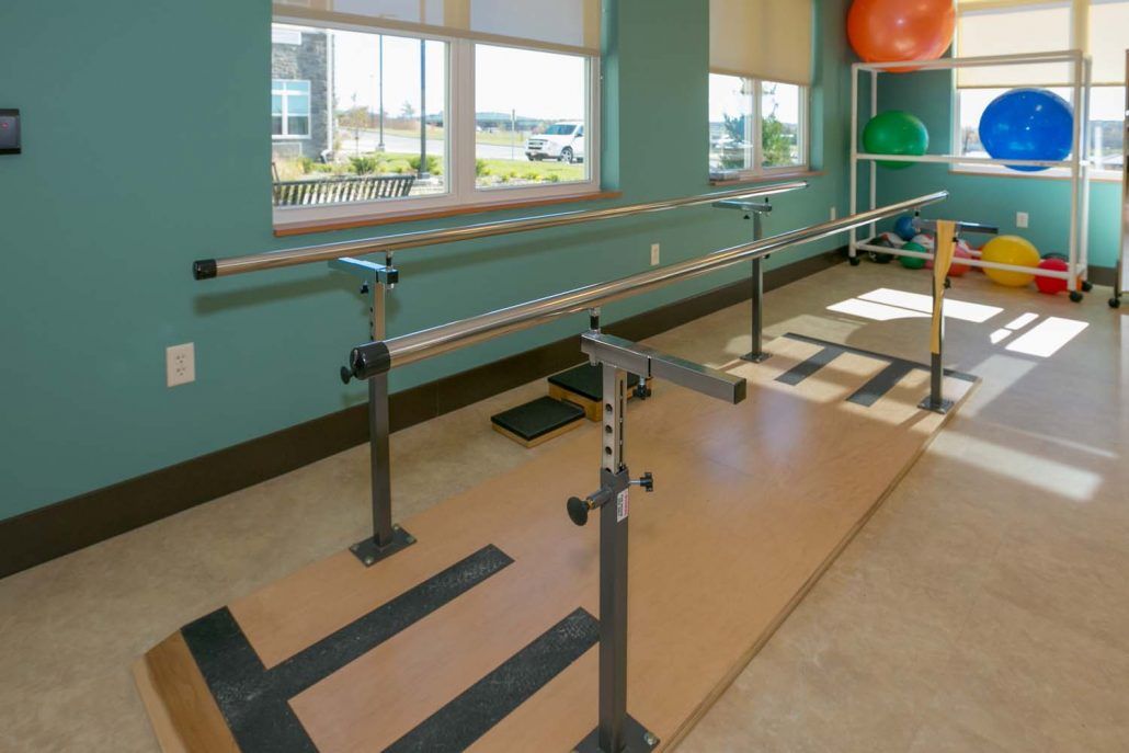 Physical therapy room equipped with parallel bars for rehabilitation exercises.