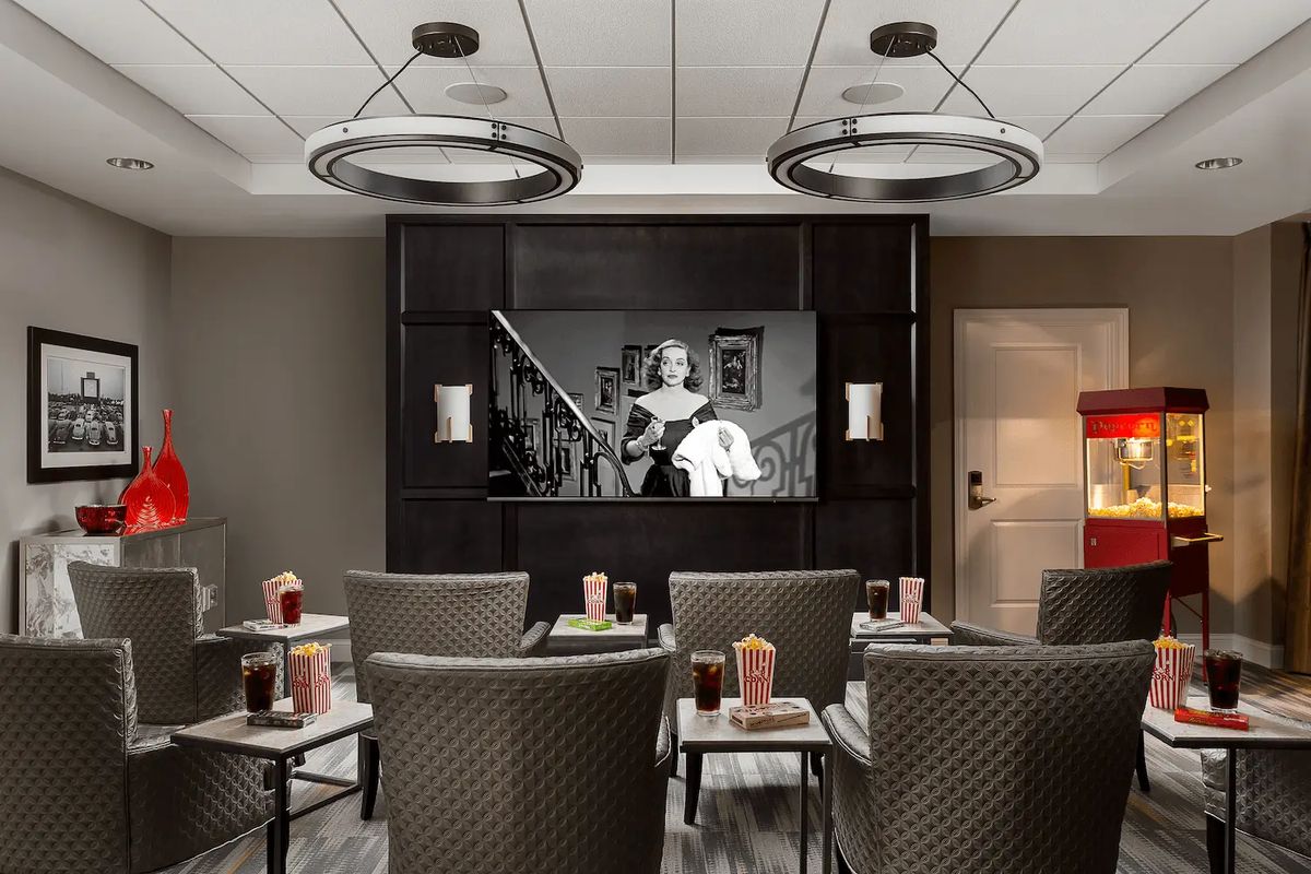 A cozy home theater setup with comfortable seating, showing a black and white film on the screen.