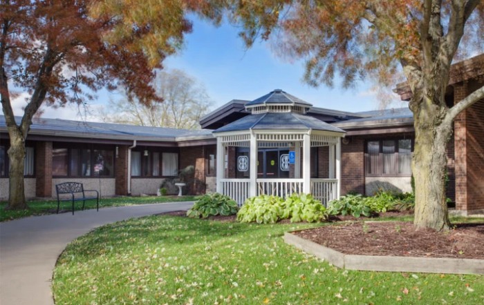 A picturesque house with a gazebo surrounded by a well-maintained garden and autumn foliage.