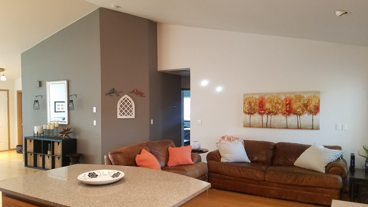A contemporary living room featuring brown leather sofas with colorful cushions, modern wall art, and a neutral color scheme.
