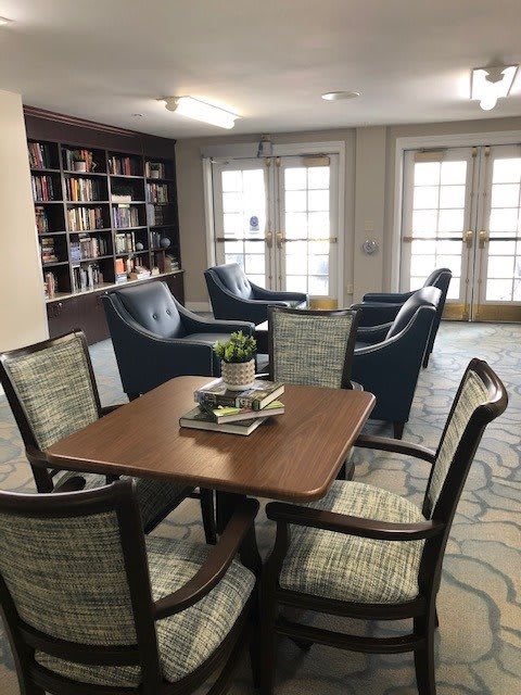 A cozy reading area with a table and chairs surrounded by bookshelves.