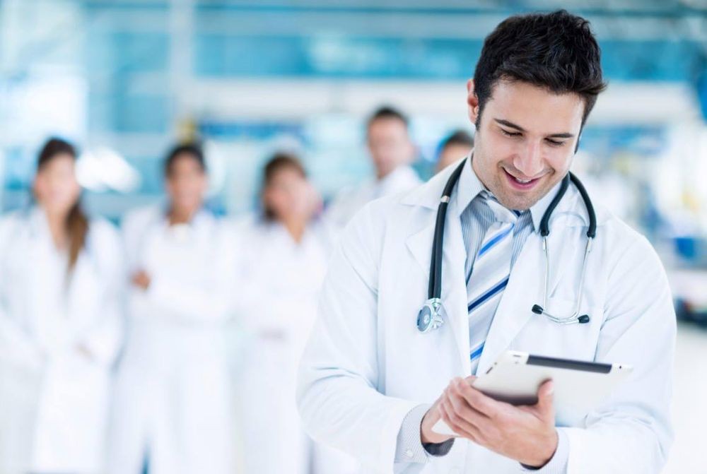 A group of doctors, with one in focus using a tablet.