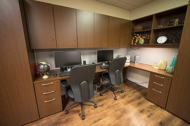 A tidy office space with two workstations and wooden cabinets.