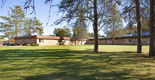 A peaceful outdoor view of a residential building surrounded by lush greenery and trees.