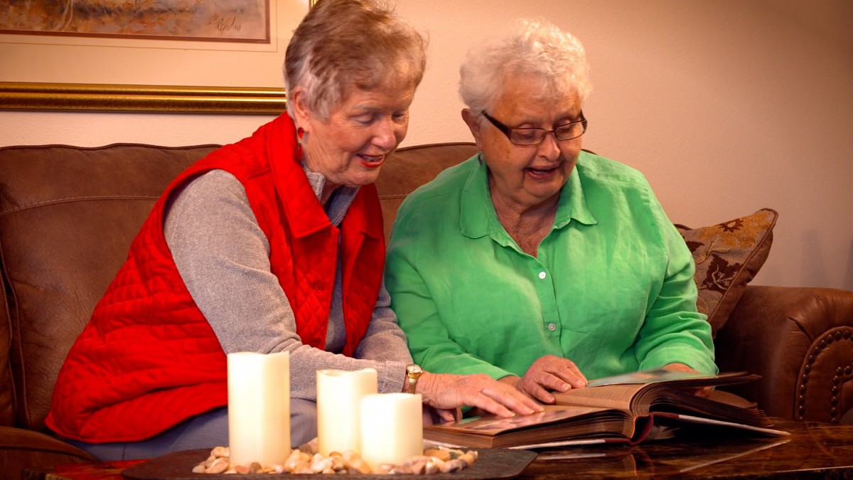 Two elderly women enjoying reading together in a cozy setting.