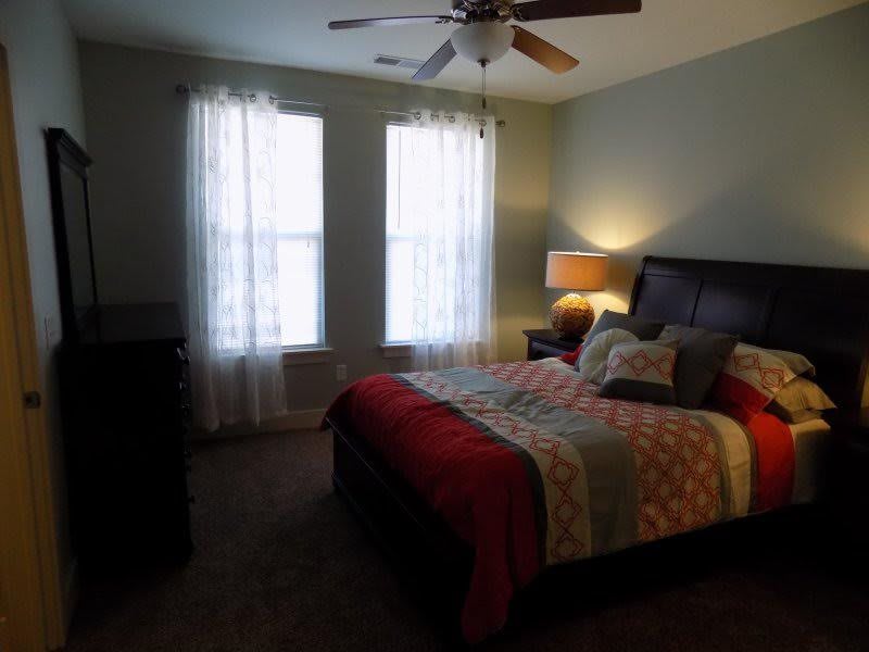 A cozy bedroom with a bed, curtains, and a bedside lamp.