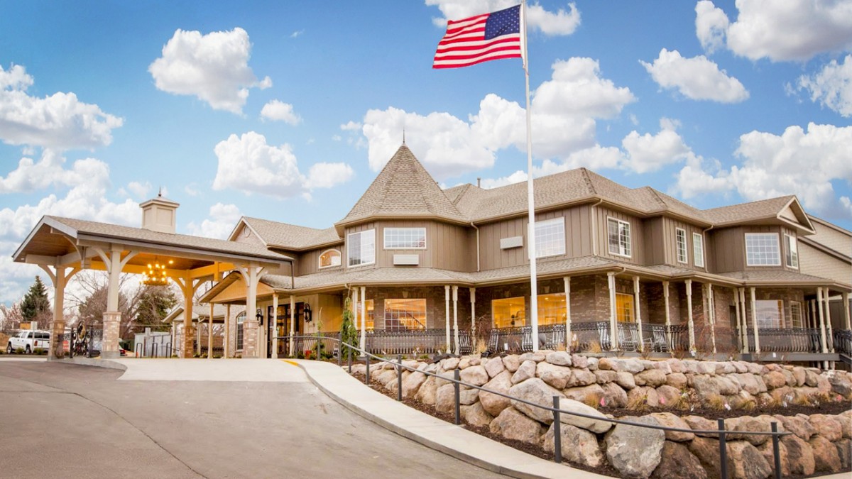 A hotel building with an American flag waving against a blue sky with clouds.