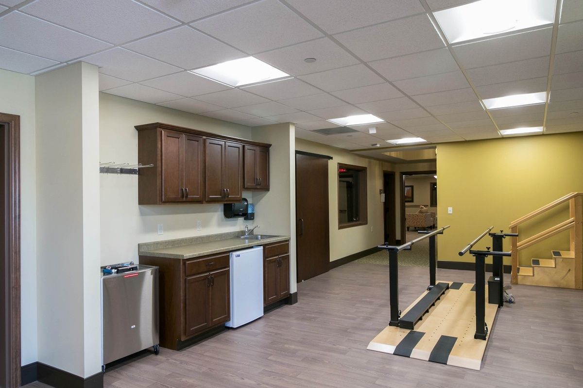 A modern office break room with a kitchen area featuring cabinets, a sink, and countertop space.