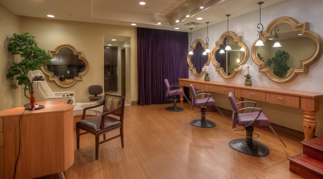 An elegant salon interior featuring chairs, mirrors, and soft lighting.