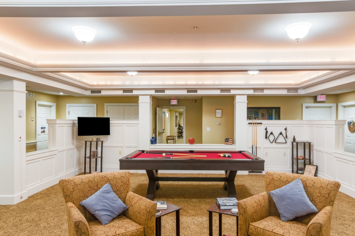 A stylish game room featuring a red pool table and comfortable seating.