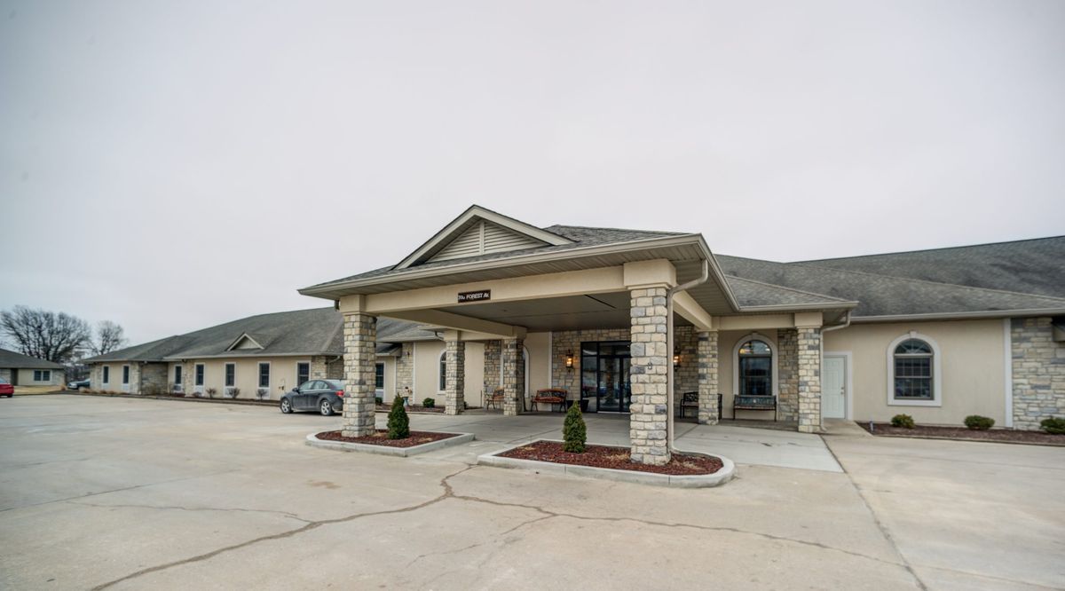 A front view of a building with a covered entrance and a parking lot.