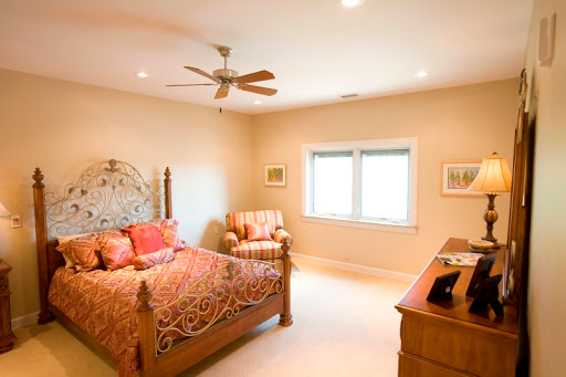 A cozy and well-lit bedroom featuring a stylish bed, comfortable chair, and natural light from the windows.