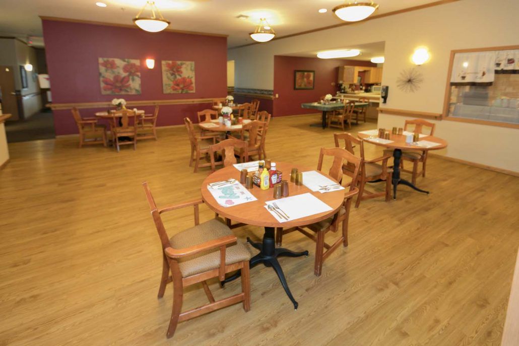 A warm and inviting restaurant dining area with wooden tables and chairs arranged neatly on a hardwood floor.