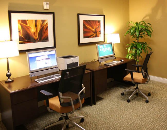 A modern office space with two workstations, featuring computers, chairs, and decorative artwork on the walls.
