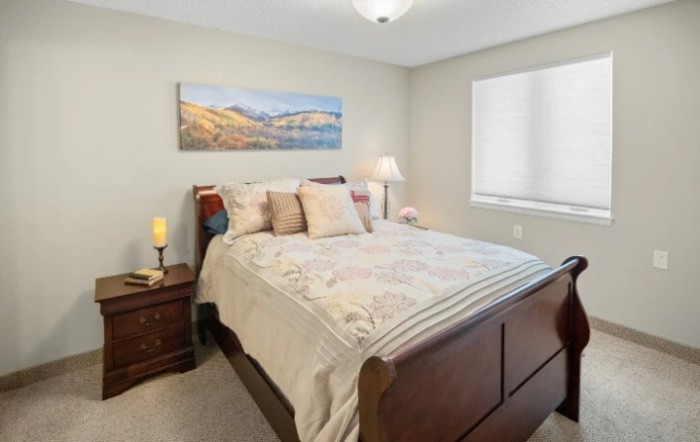 A cozy bedroom with a bed, nightstands, and decorative artwork on the wall.